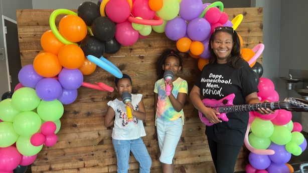 Elan and kids with inflatable music toys and balloon archway.